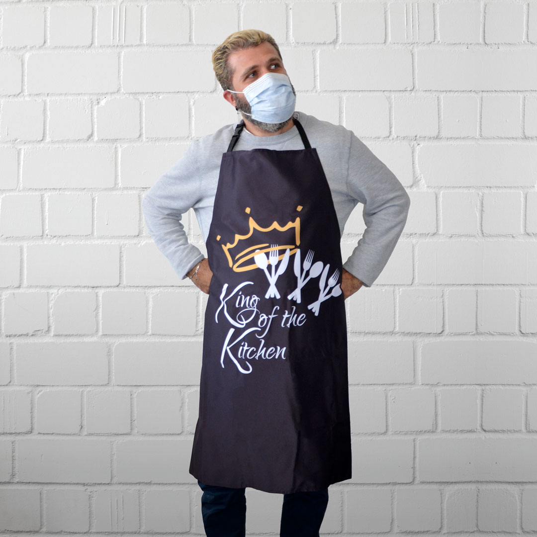 Eine Person trägt eine Kochschürze mit dunkel bedruckter Bespannung